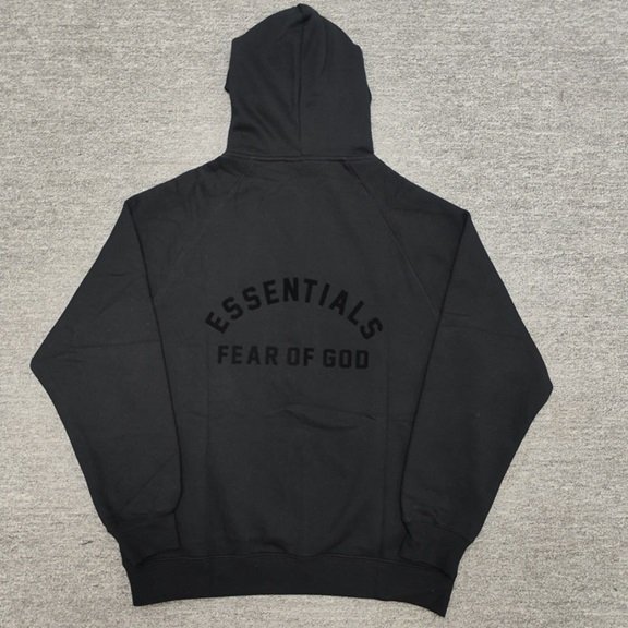Black hoodie with "ESSENTIALS FEAR OF GOD" logo, streetwear fashion, popular K-pop merch style, comfortable casual wear, unisex oversized hoodie.