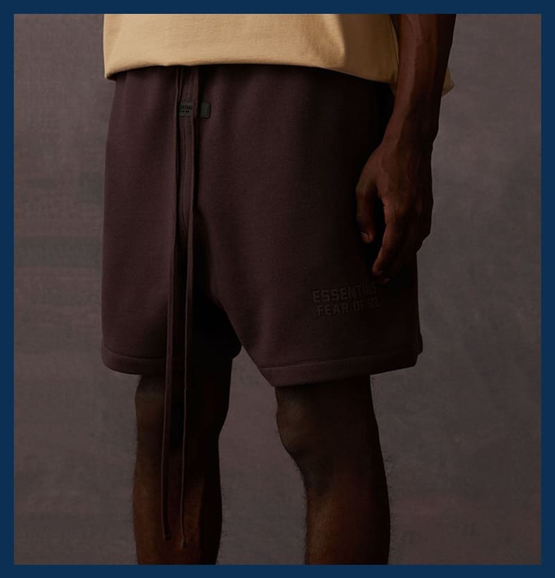 Shorts with "Essential Fear" text and a beige top; focus on the lower body and legs.