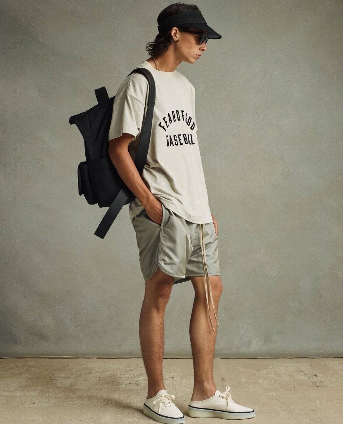 Backpack, casual t-shirt, shorts, trendy sneakers, and sunglasses exhibit modern K-pop merchandise style.