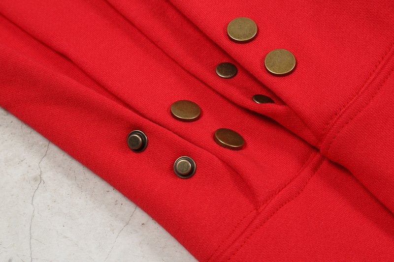 Red hoodie with metal snap buttons, close-up image of two layers of fabric featuring black and gold accents.