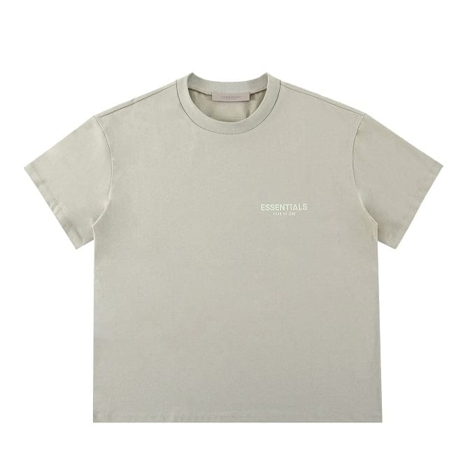 Plain beige T-shirt with "ESSENTIALS" text and small print, casual streetwear style, ideal for K-pop merchandise fans.