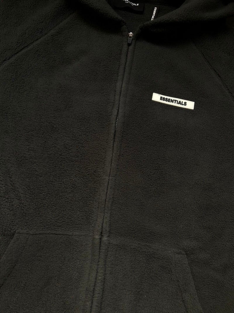 Black essentials fleece hoodie with zipper and label.