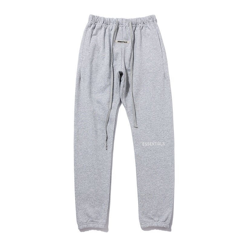 Grey kpop merch sweatpants with "ESSENTIALS" print, relaxed fit, drawstring waist, casual streetwear style, comfortable and trendy for K-pop fans.