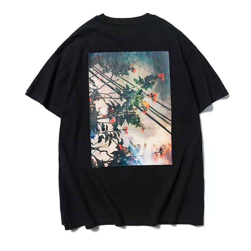 Black oversized T-shirt featuring a colorful graphic print of flowering plant silhouettes against a sky background. Perfect for K-pop merch fans and streetwear lovers.