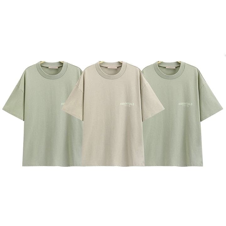 Soft pastel green and beige twin kpop merch t-shirts with "ESSENTIALS" text on front, casual oversized style, perfect for fans of K-pop groups.
