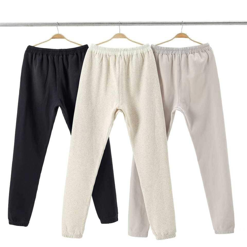 Black, beige, and light grey jogger pants hanging on hangers.