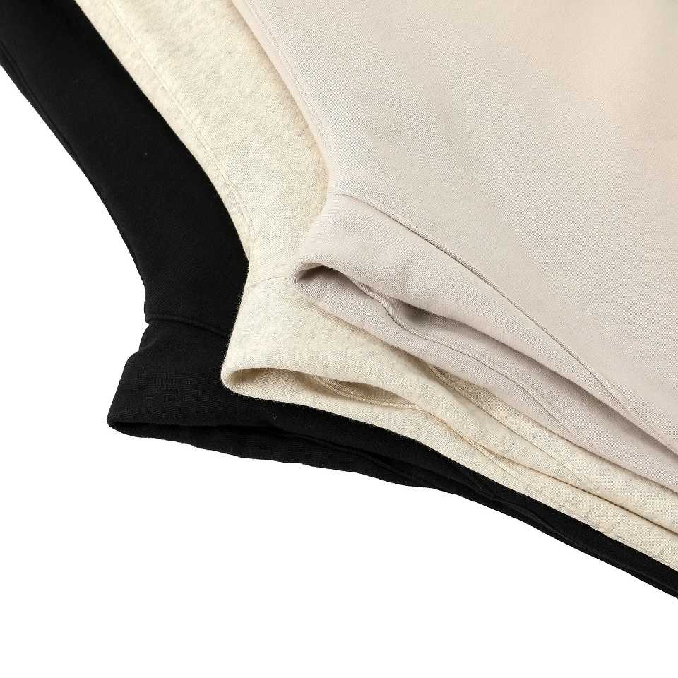 Black and beige K-pop merchandise layered clothing items, possibly t-shirts or sweatshirts, neatly folded for display or sale. The image captures close detail of fabric textures and stitching.