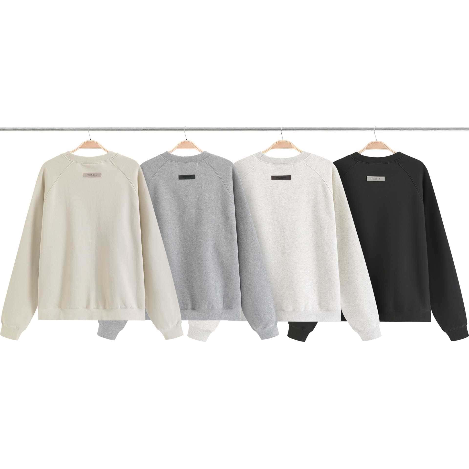 Crewneck sweatshirts in neutral colors hanging on a clothing rack, perfect for casual wear and K-pop merchandise collections.