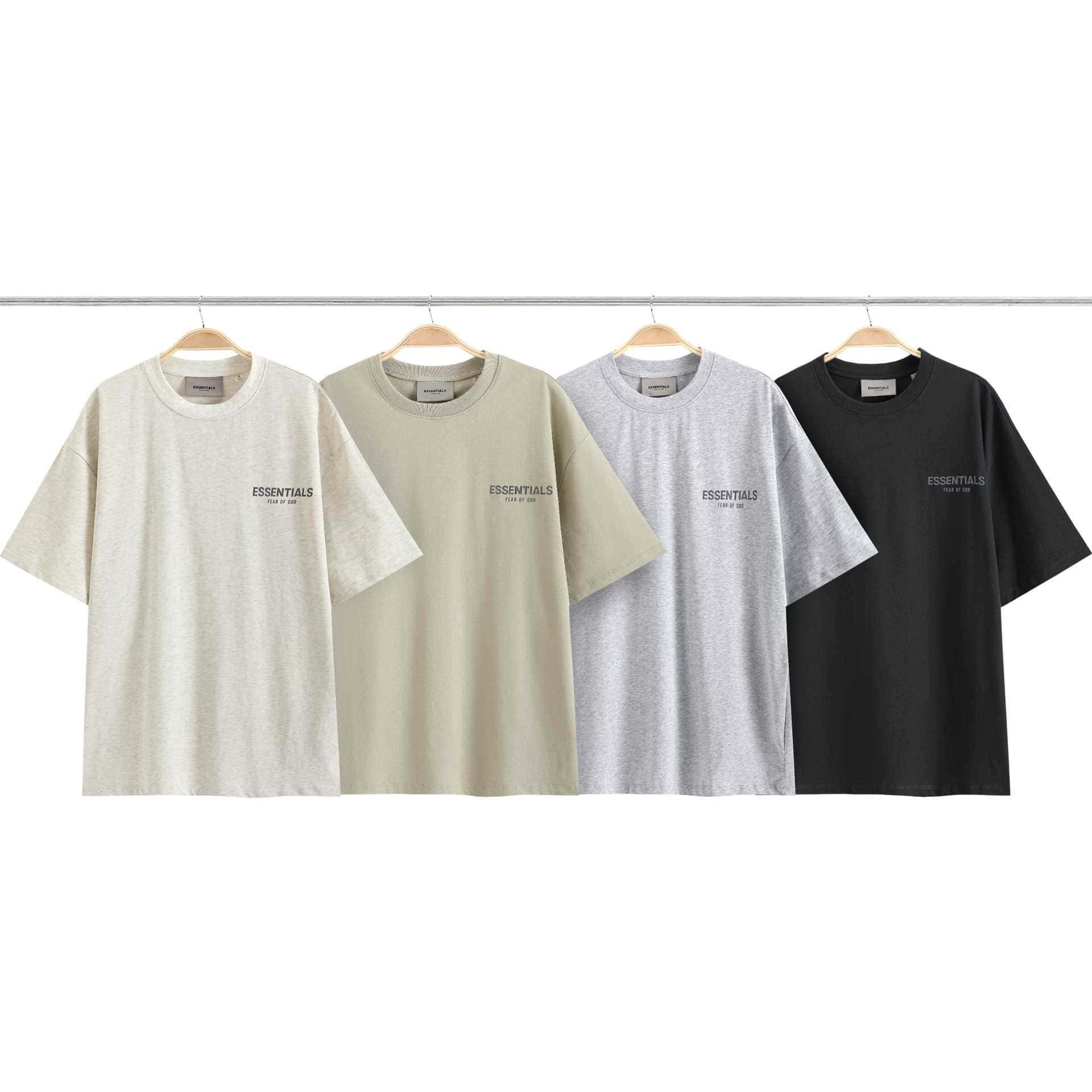 Oversized K-pop merchandise T-shirts in neutral colors with "ESSENTIALS" print, hung on wooden hangers, perfect for fans to showcase their love for K-pop.