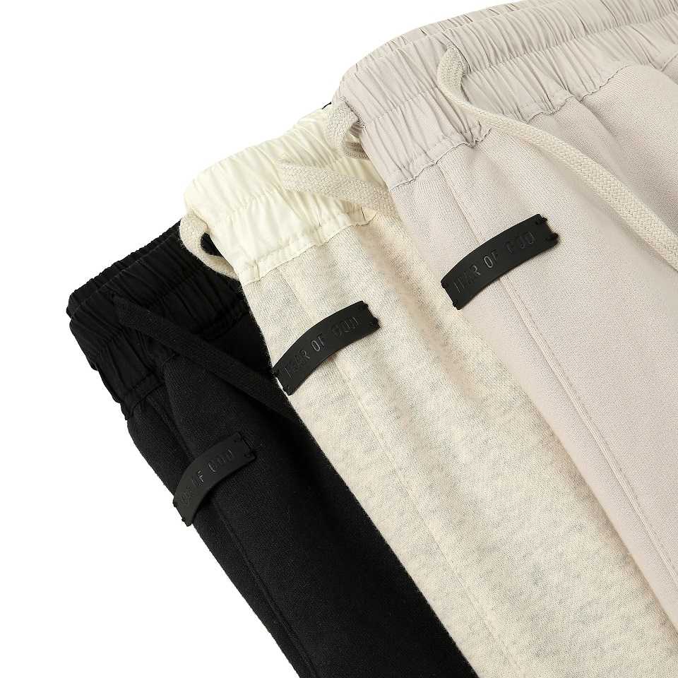 Black, beige, and white twopack kpop merchandise sweatpants with adjustable drawstrings and brand tags, casual and trendy apparel for K-pop fans.
