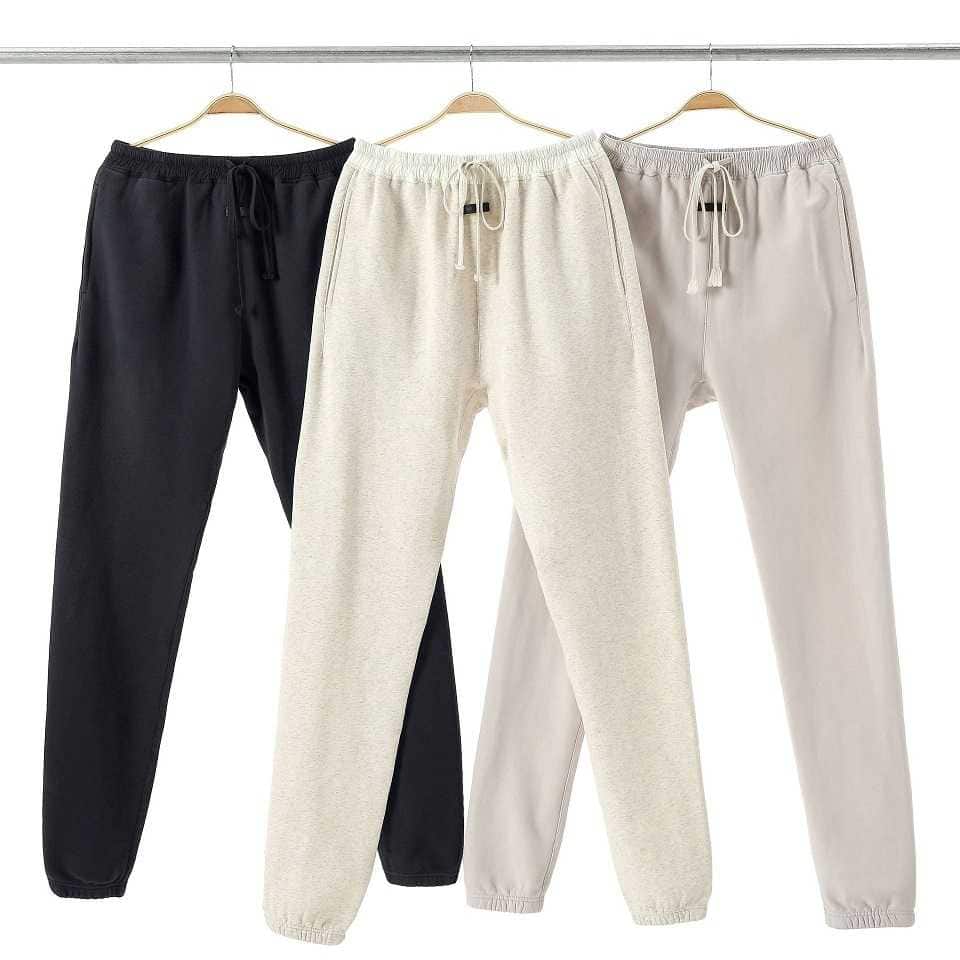 Black, white, and beige jogger sweatpants hanging on hangers, cozy casual loungewear, popular in K-pop merchandise fashion, comfortable and stylish for fans of Korean pop culture.