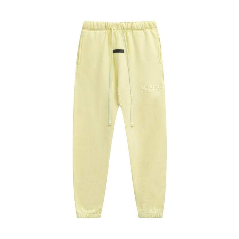 Yellow sweatpants with black detail and "ESSENTIALS FEAR OF GOD" embroidered on the side, perfect for casual K-pop fashion and merchandise collections.