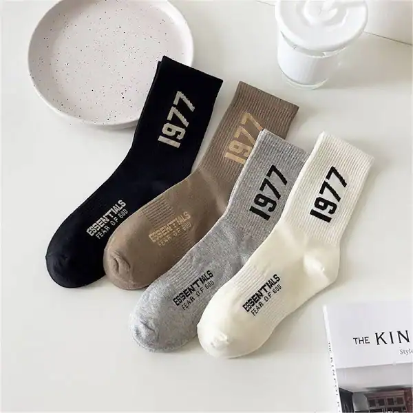Cute K-pop merchandise: four pairs of stylish socks in black, beige, gray, and white, each featuring bold "1977" text and "Essential Details" print, perfect for fans and collectors.