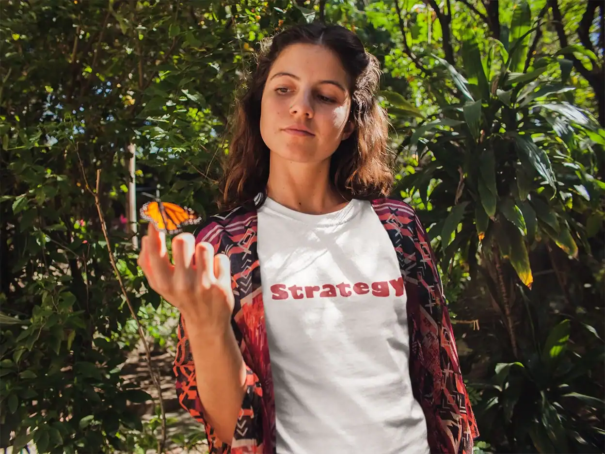 Butterfly on woman's finger, woman outdoors with greenery, casual woman, nature, close-up of woman with butterfly, garden scene, natural light, serenity, casual fashion, outdoor activity.